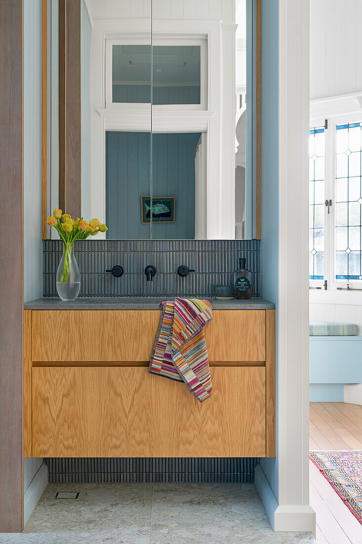 Washbasin with wooden front and mirror above, placed between room divider walls