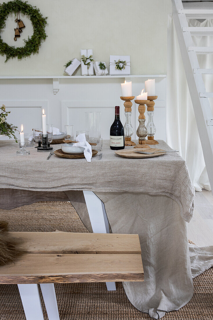 Dining table decorated with linen, candles and fresh branches