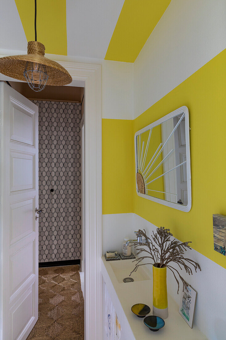 White bathroom with narrow sink and yellow accents