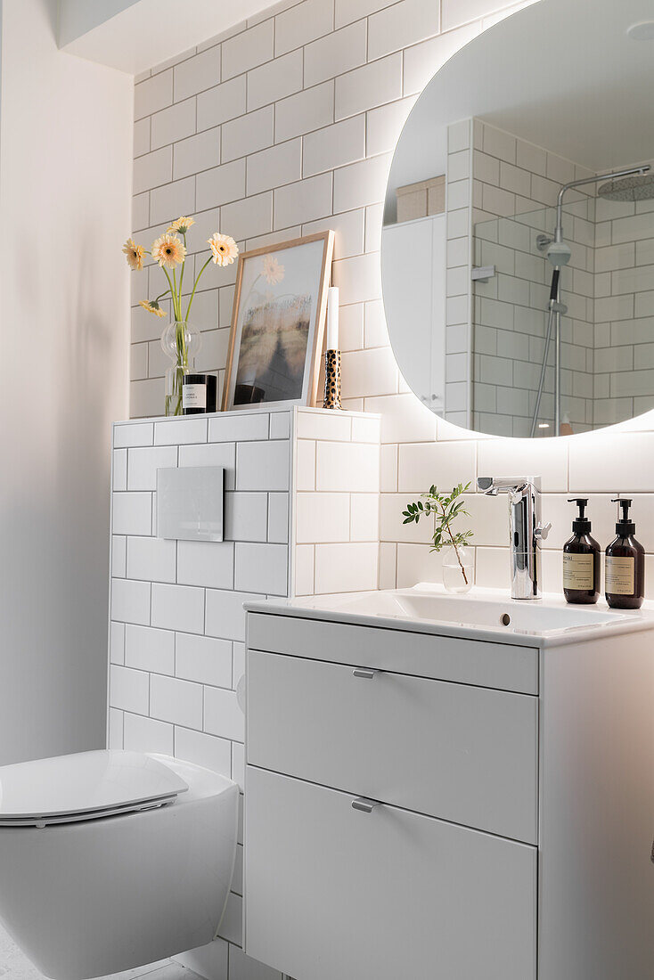 Sink in light-colored bathroom with white wall tiles