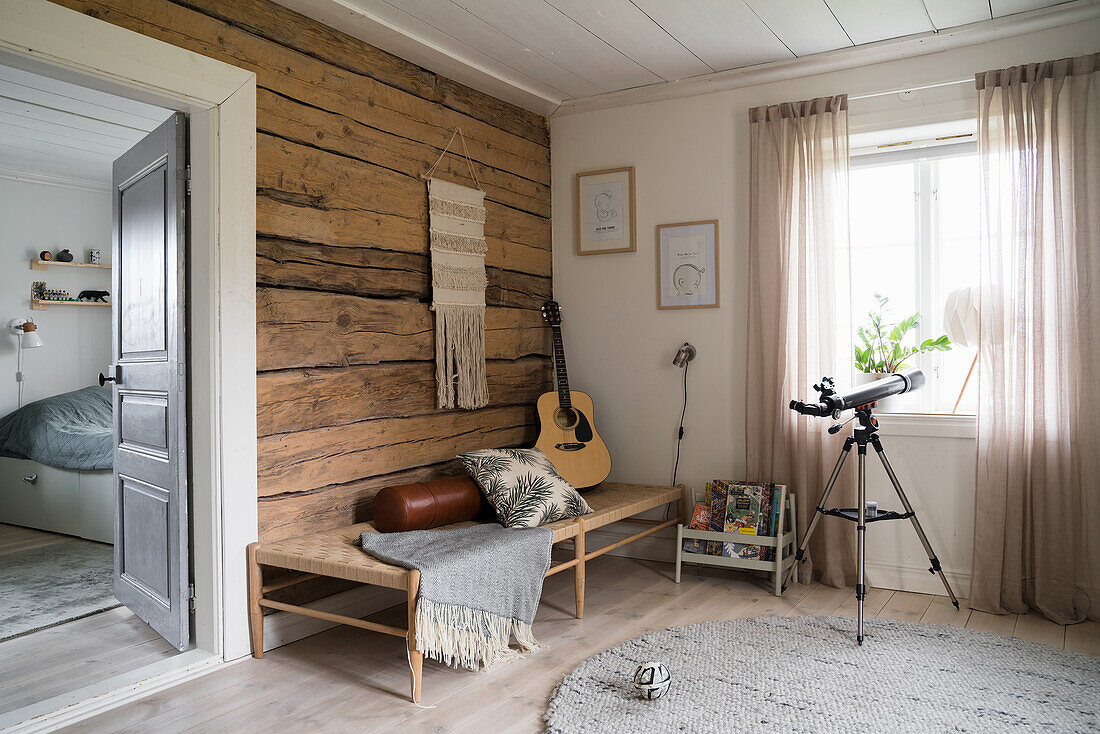 Cozy room with guitar, telescope and wooden accents, view into the bedroom