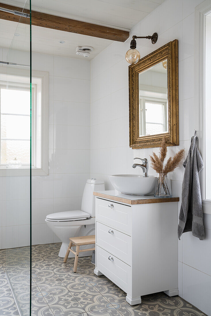 Sink and gold-framed mirror in bright bathroom with grey patterned floor tiles