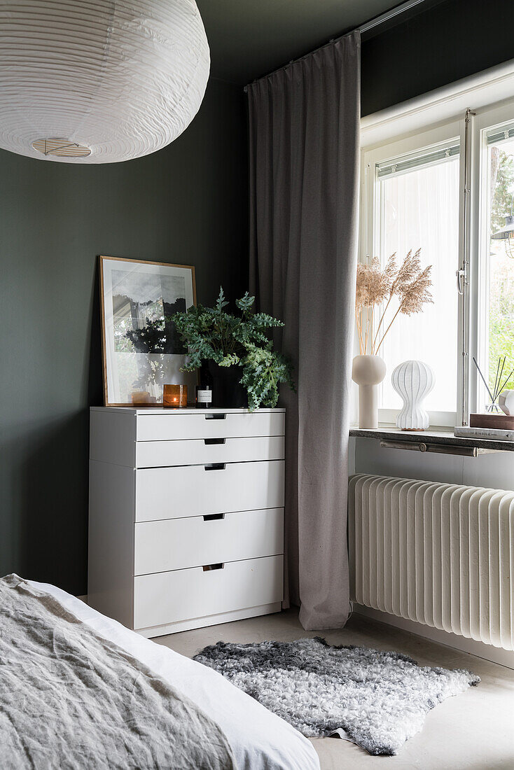 Weißer Schubladenschrank und Schaffell im Schlafzimmer mit grünen Wänden