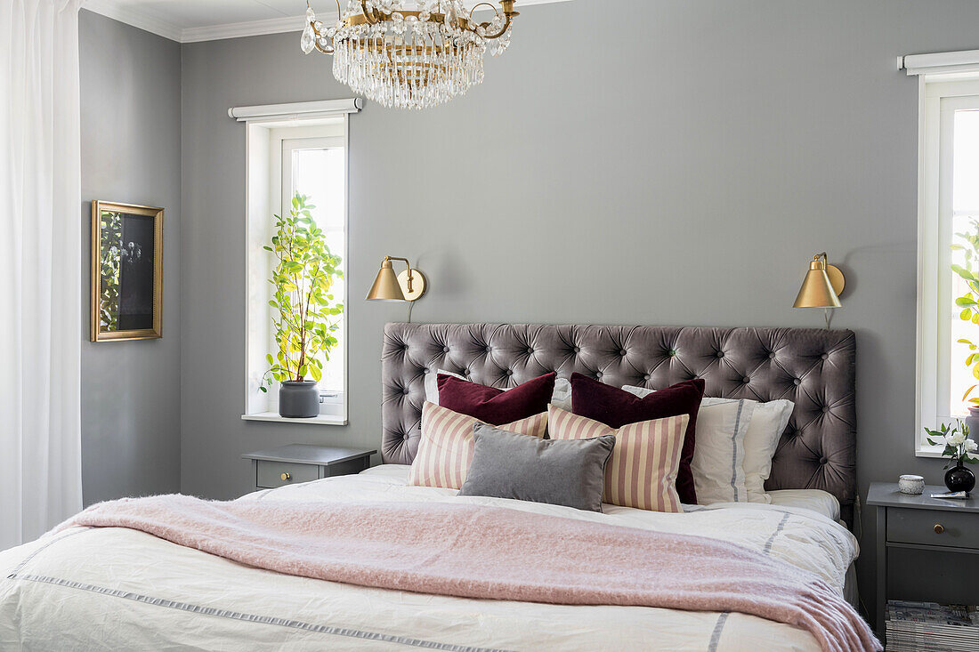Double bed with capitoned headboard in the bedroom in grey tones