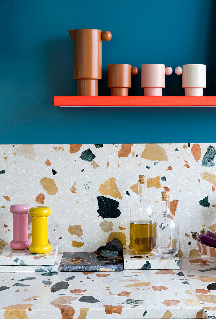 Küchenarbeitsplatte und Spritzschutz aus Marmorterrazzo, darüber Regal an blauer Wand