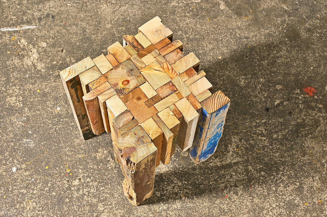 Hocker aus recyceltem Holz mit Mosaikmuster auf Betonboden