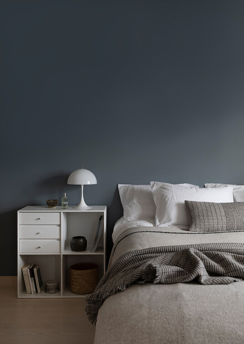 Doppelbett und Nachtkästchen vor grauer Wand