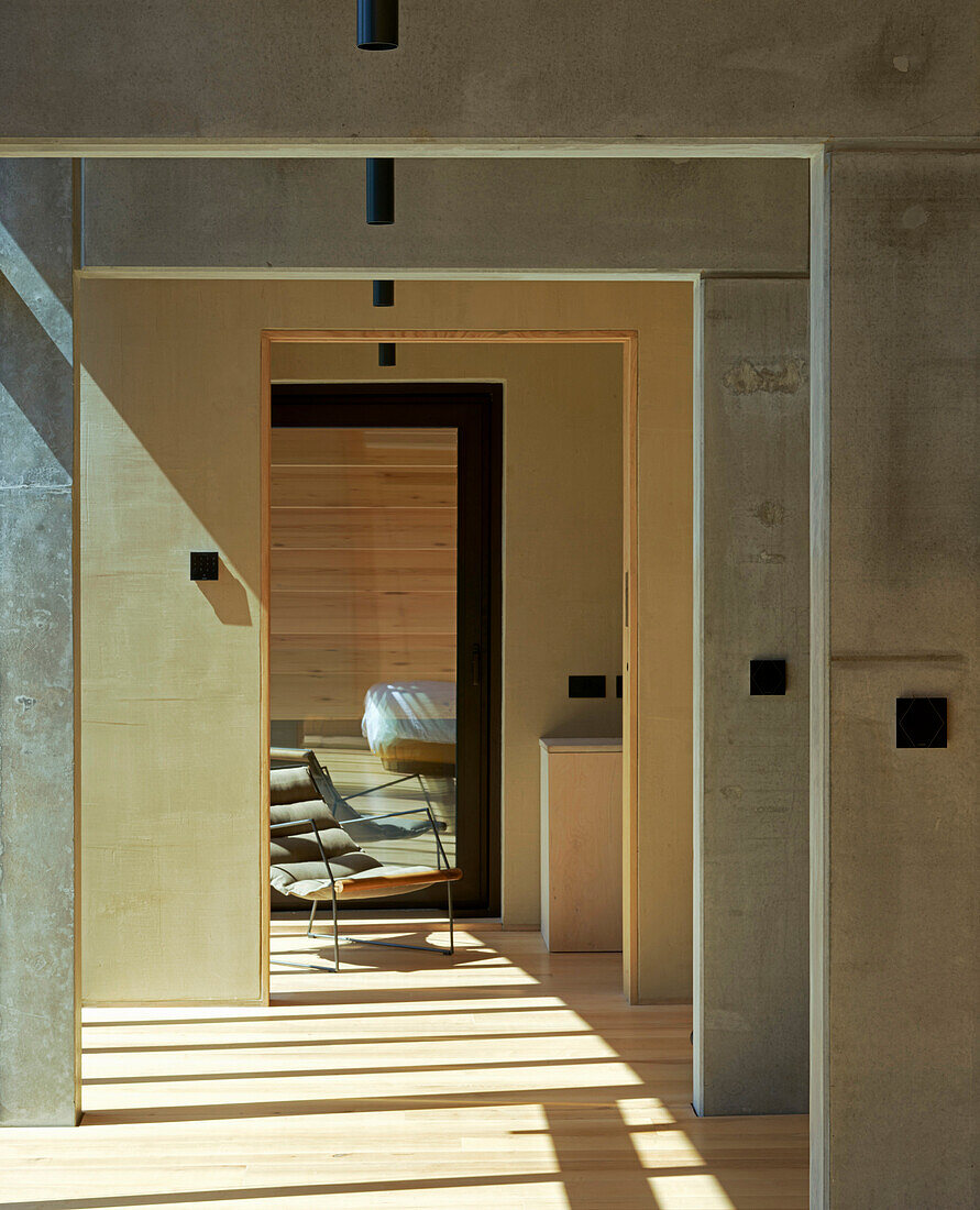 Lichtdurchfluteter Flur mit hellem Holzboden und Betonwand im Architektenhaus
