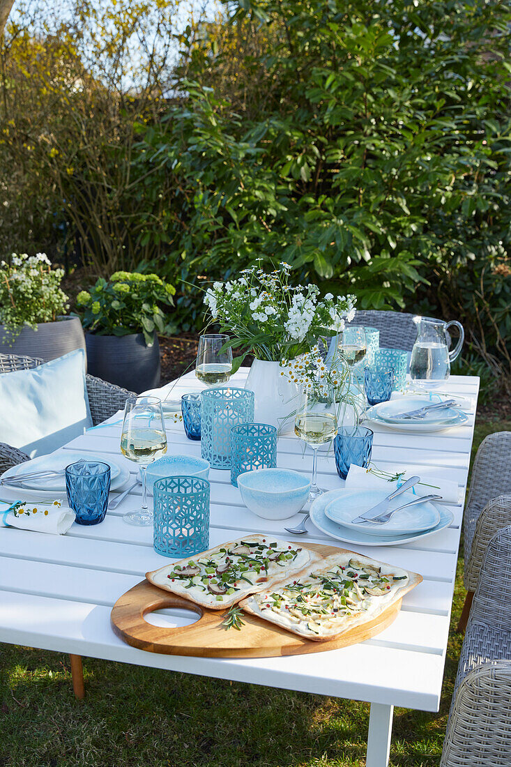 Table set with glasses and candle lanterns in shades of blue in the garden
