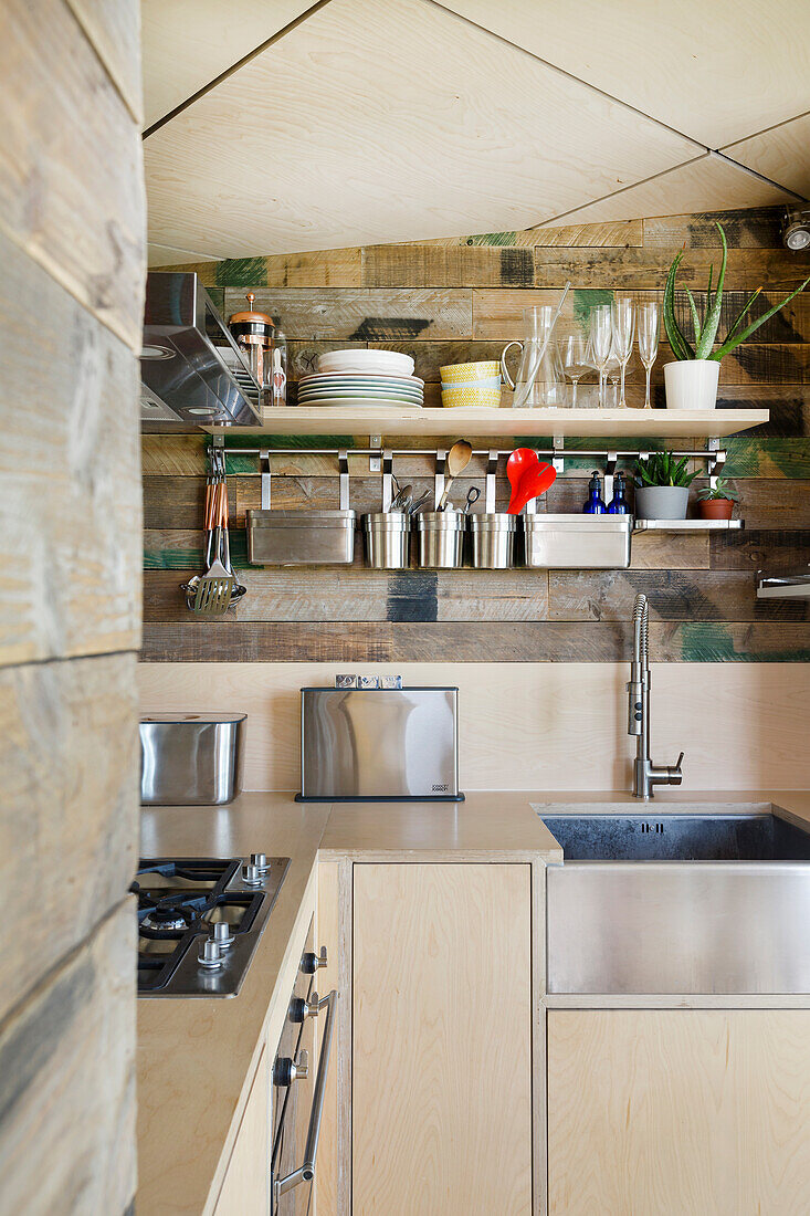 Küche mit Schränken aus Sperrholz und Wänden aus Holzkisten