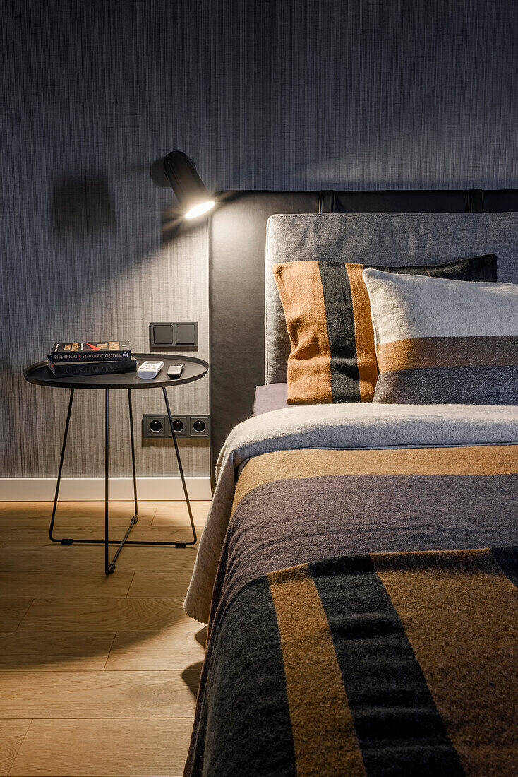 Reading lamp next to bed in bedroom in black and grey tones