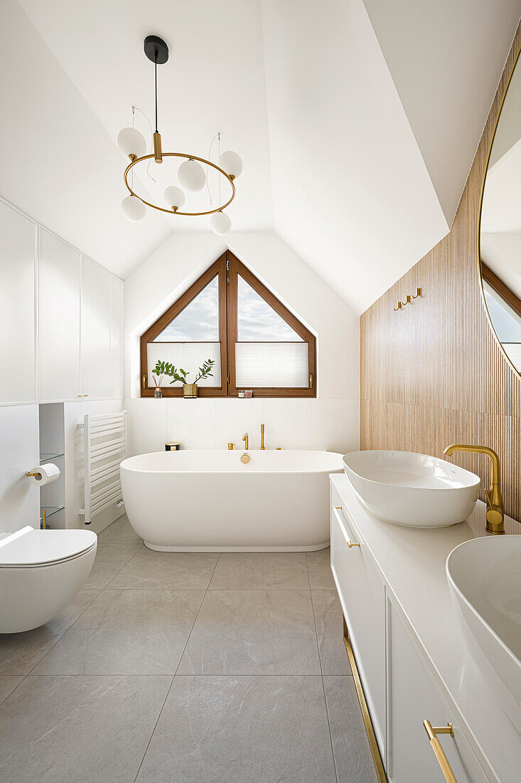 Vanity and freestanding bath under window in white bathroom