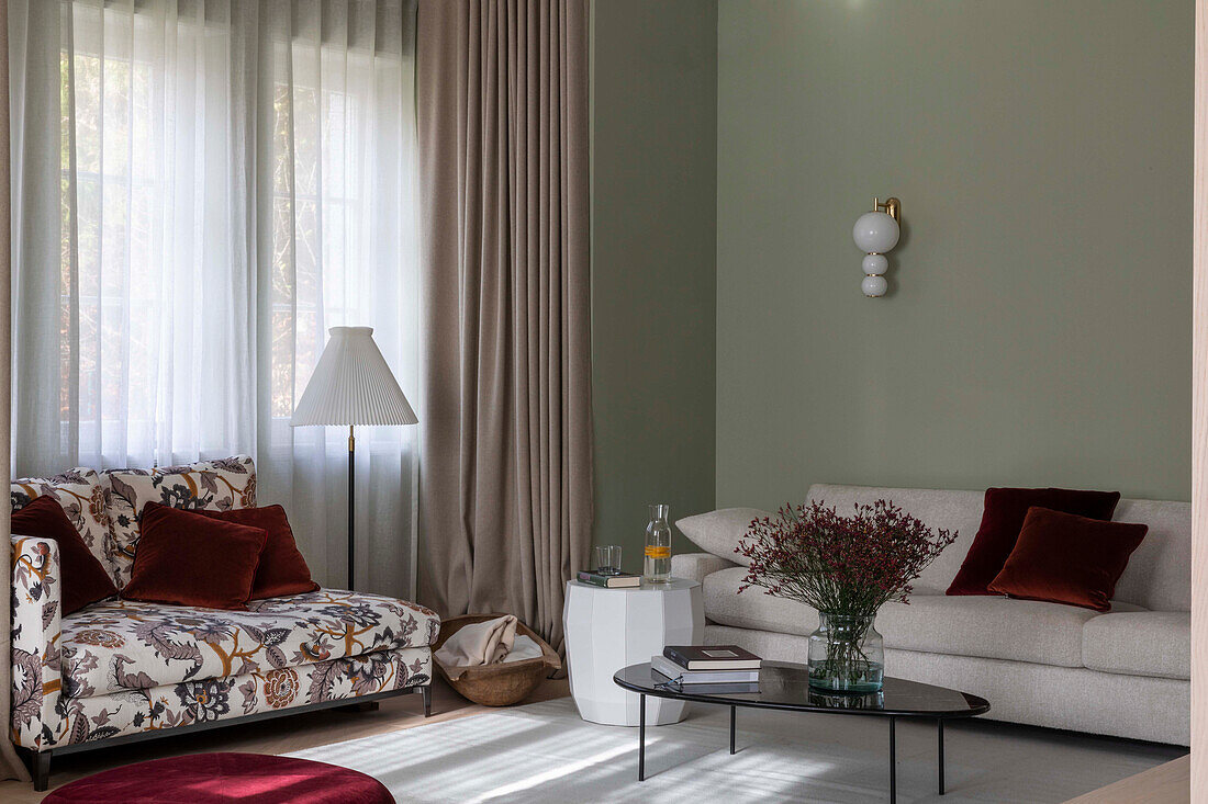 Geblümtes Sofa, helles Sofa und Coffeetable im Wohnbereich mit bodenlangen Vorhängen und grünen Wänden