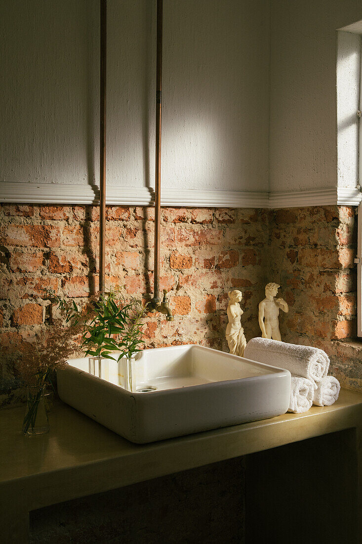 Sink with countertop basin in front of exposed brick wall