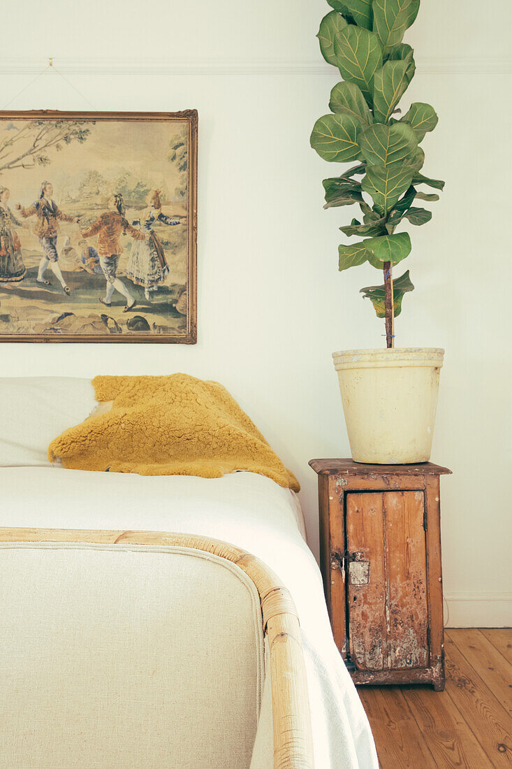 Doppelbett, daneben Vintage Nachtschränkchen mit Zimmerpflanze