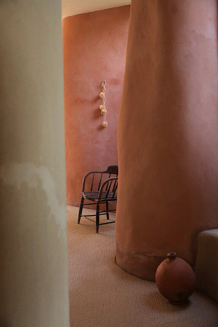 Curved passageway in terracotta colors with seating area