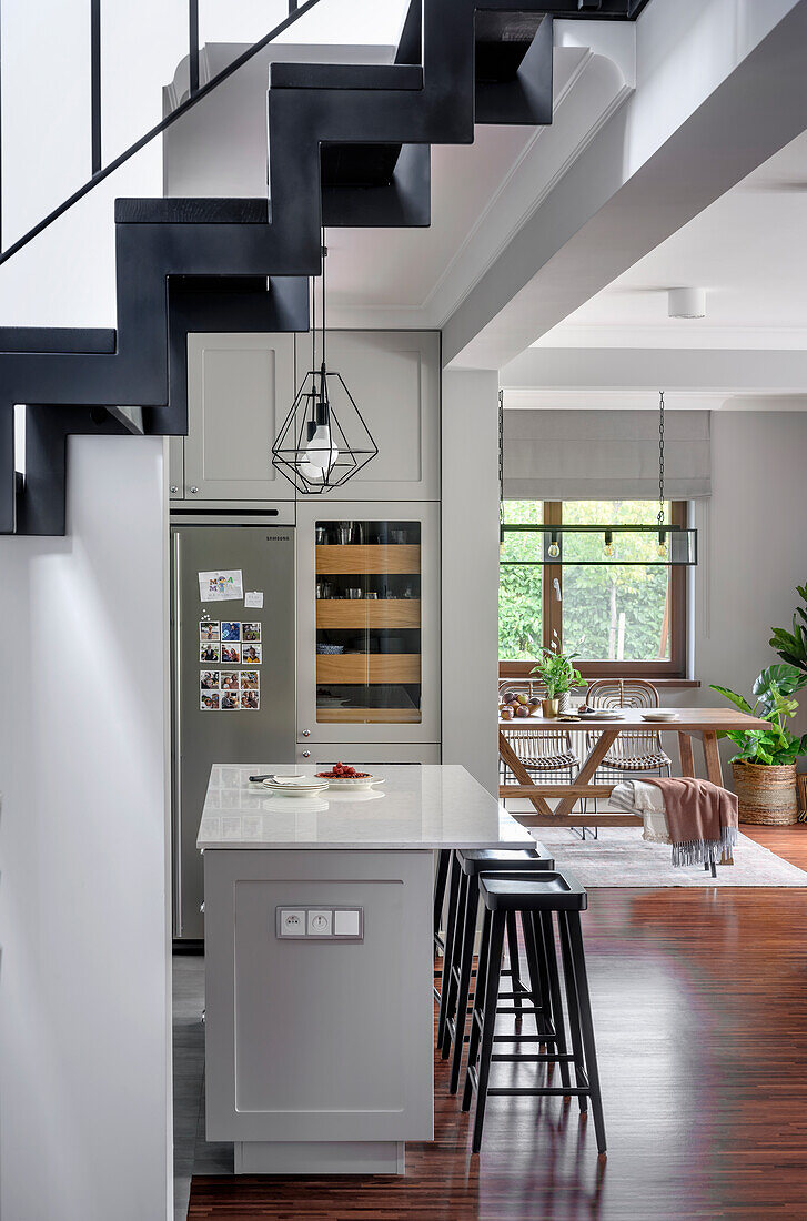 Weiß-graue Küche mit Kücheninsel, Blick ins Esszimmer, Treppe im Vordergrund