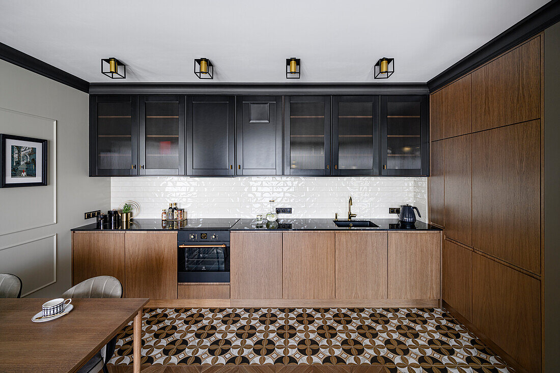 Fitted kitchen cabinets with black wall mounted units and base units with walnut veneer and patterned floor tiles