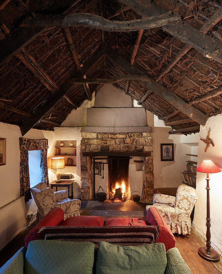 Rustikaler Wohnraum mit Kamin, gemütlichen Sitzmöbeln und Torfdach in traditionellem Bauernhaus, Irland