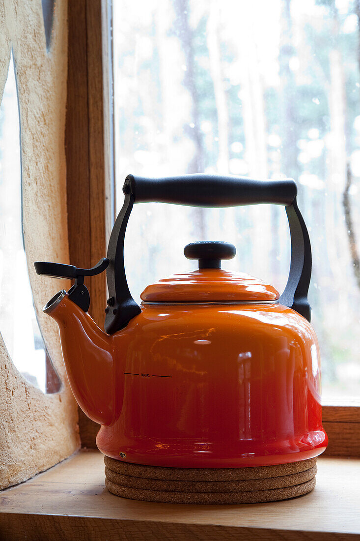 Red tea kettle on windowsill