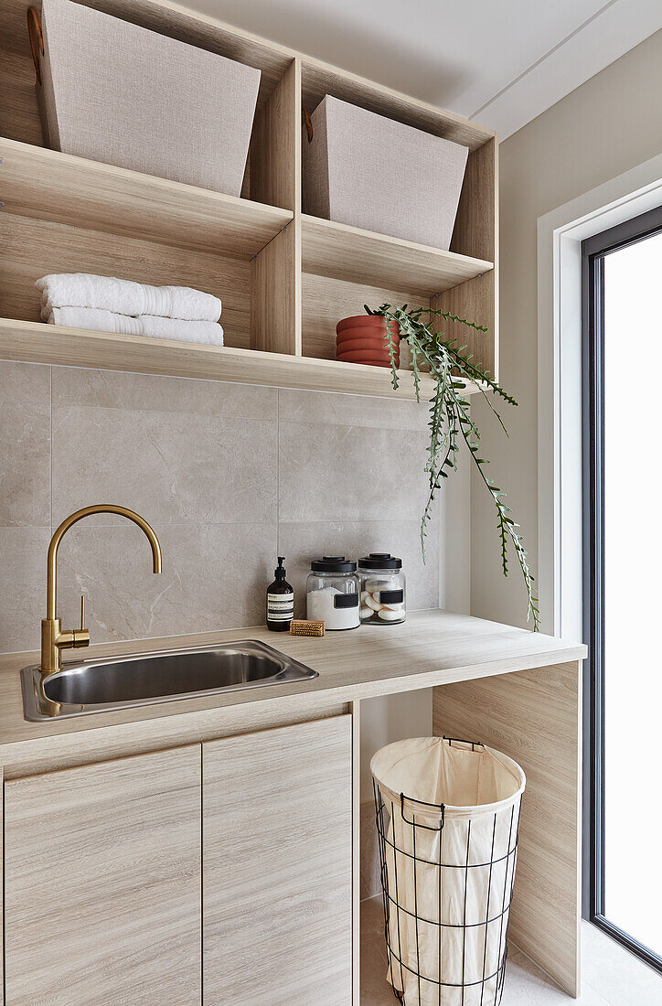 Moderne Waschküche im Scandi-Stil mit maßgefertigten Möbeln aus Buchenholz und goldenem Wasserhahn