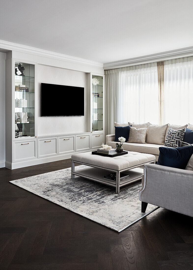 Traditional living room with cream velvet sofas, upholstered coffee table, and built-in shelves