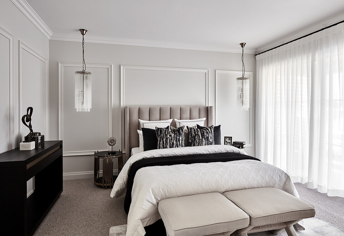 Opulent bedroom in neutral tones with paneled walls and hanging chandeliers