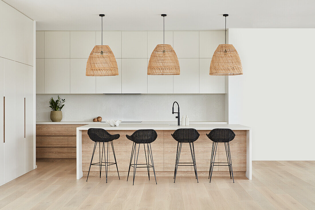 Bright Scandi-style kitchen with woven basket lights and black rattan bar stools