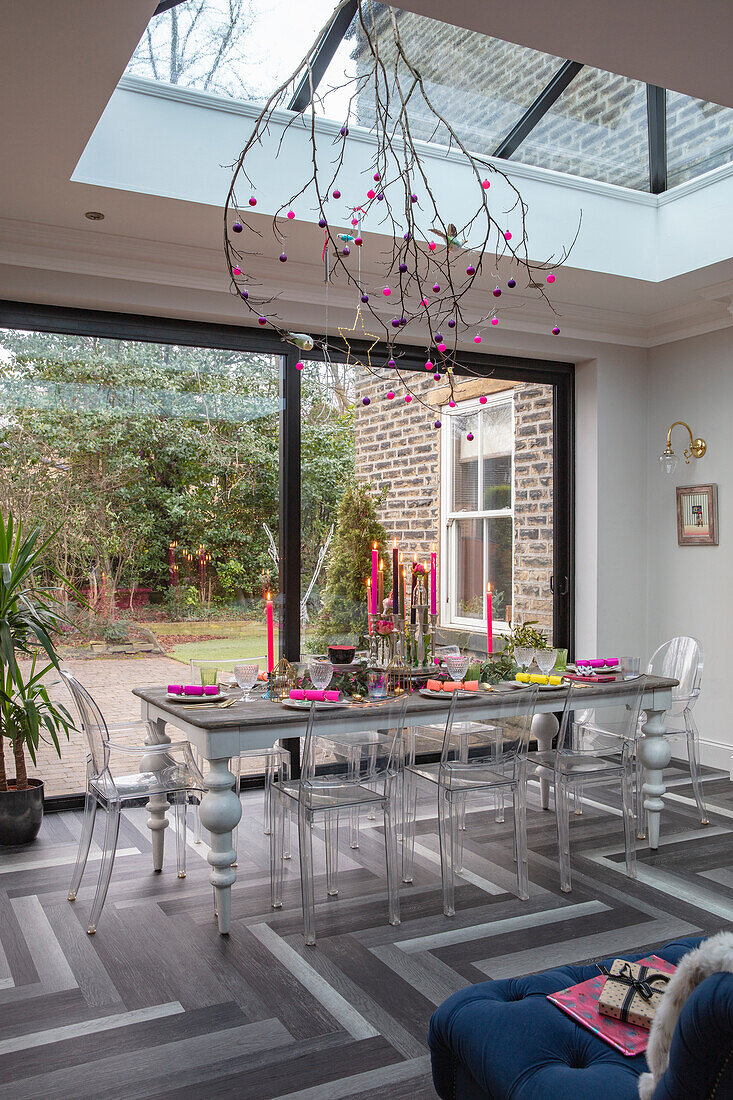 Dining room with glass roof, modern table decorations and view of the garden