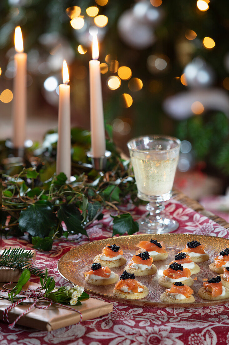 Christmas table with candles, salmon canapés and champagne-coloured presents