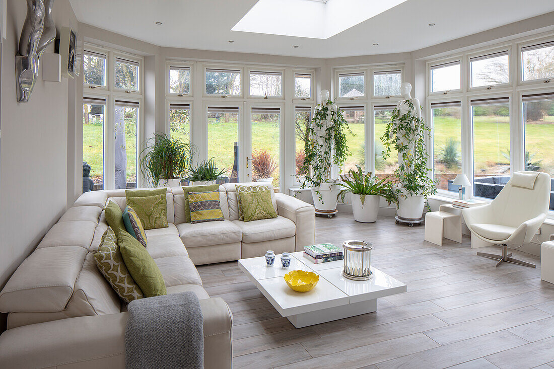 Bright conservatory living room with panoramic windows and plants