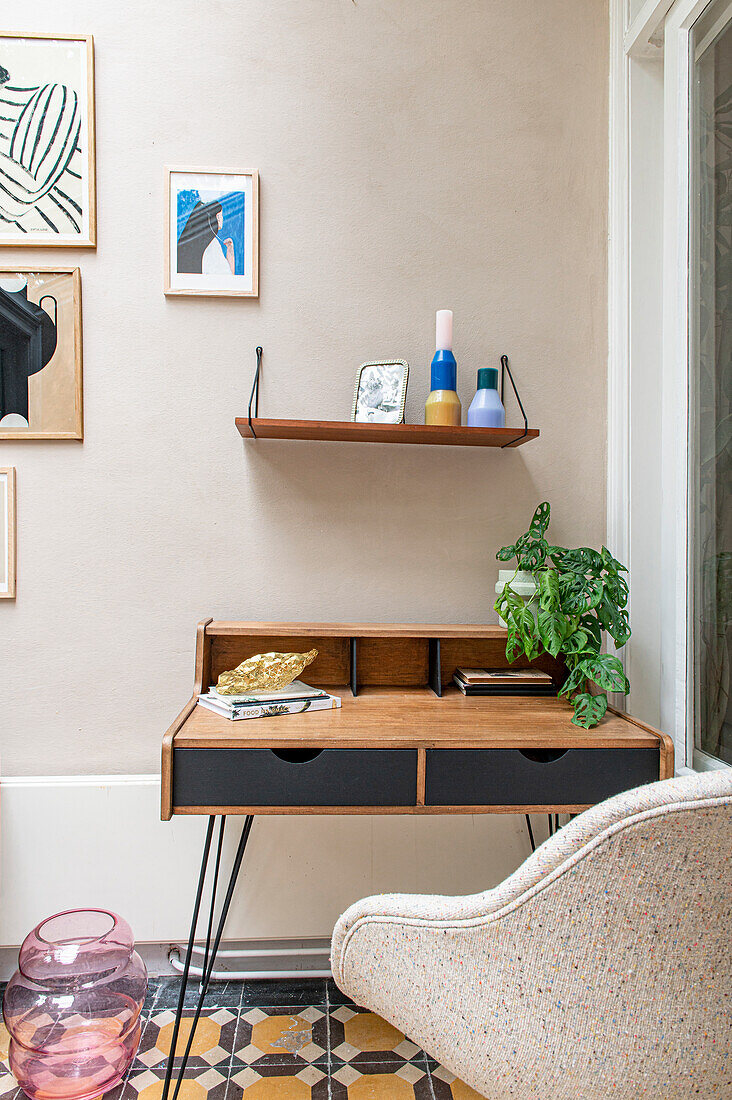 Vintage secretary with wooden shelf, armchair and houseplant