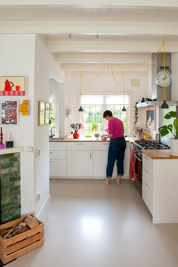 Woman in kitchen with white fronts and wooden countertop