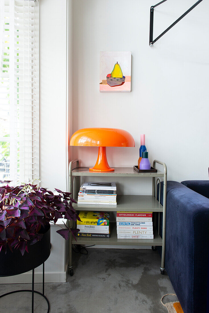 Shelf with books and orange lamp next to blue sofa