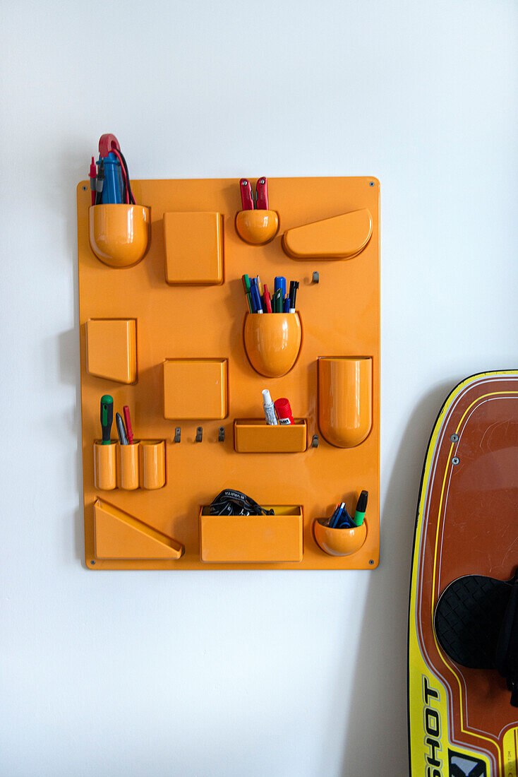 Wall organiser with pens and utensils next to snowboard