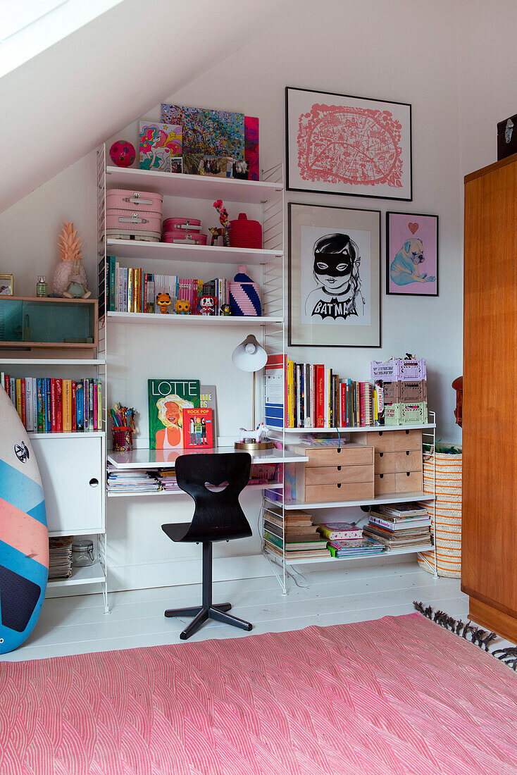 Workplace with shelf, desk and swivel chair under sloped ceiling