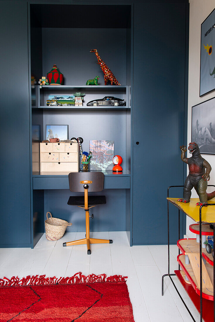 Work corner with dark blue cupboards, integrated desk and red carpet