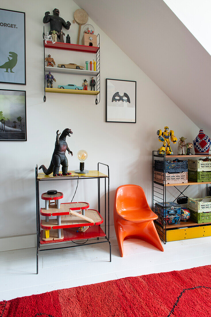 Shelf, children's toys and designer chair in the children's room with sloped ceiling