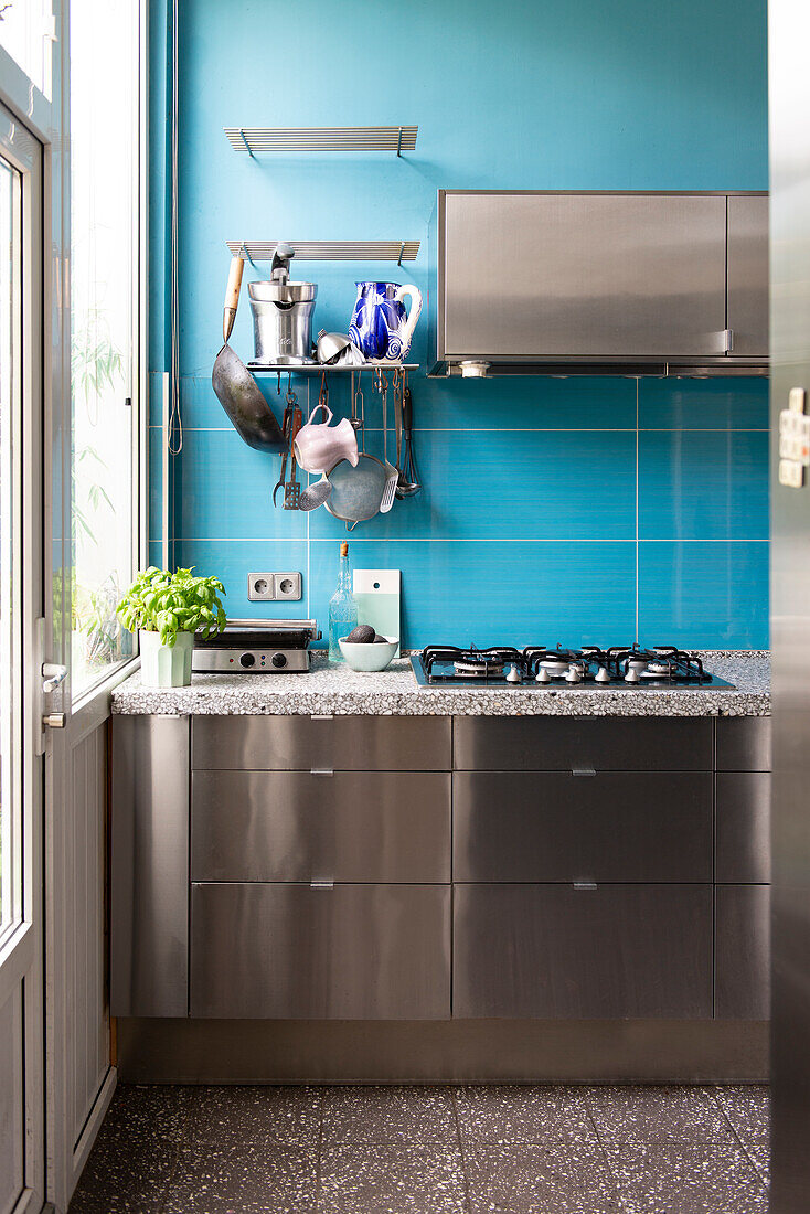 Modern stainless steel kitchen unit, gas stove and blue wall