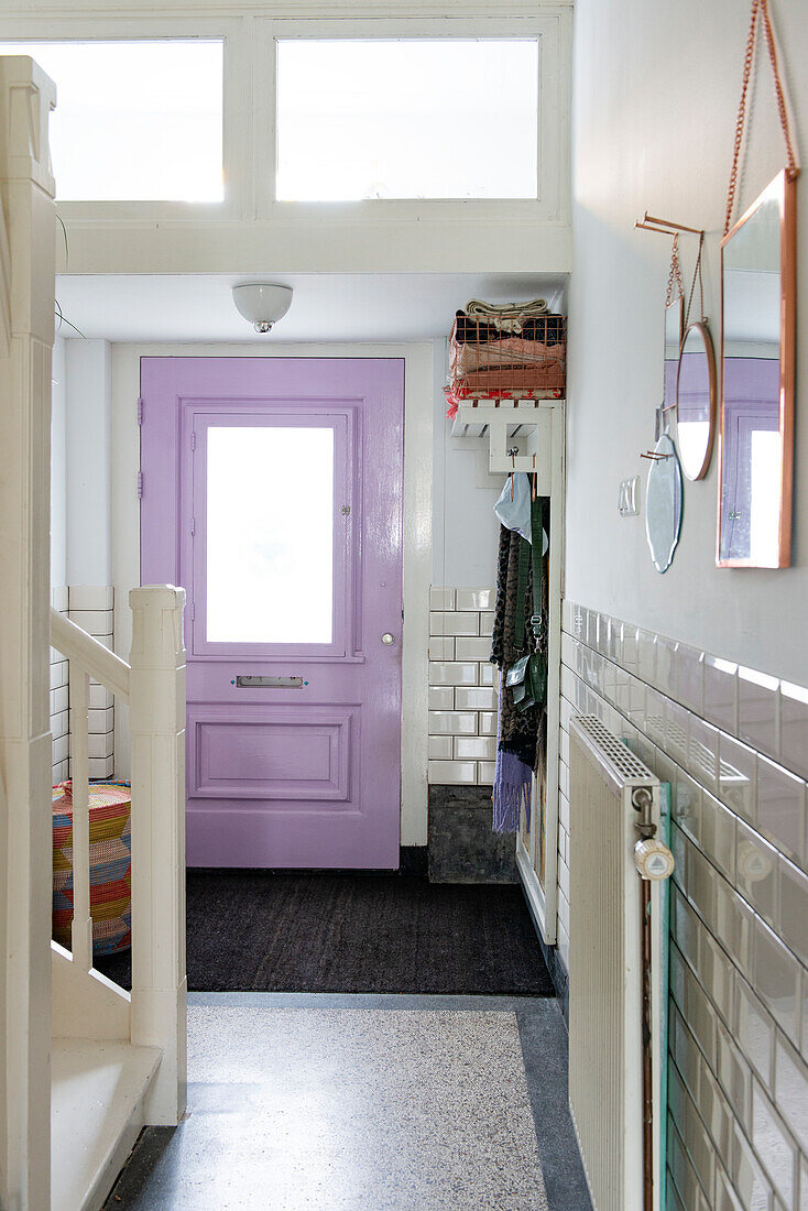 Hallway with purple front door, white walls and white metro tiles on the wall