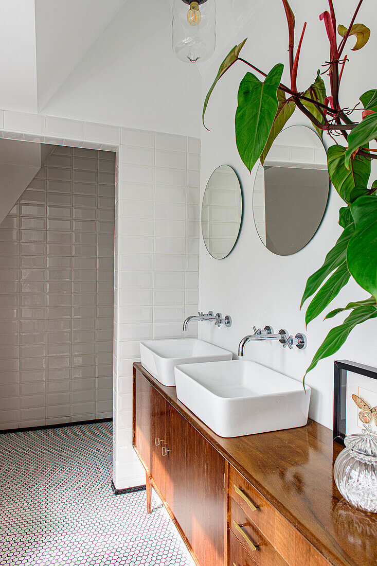 Bathroom with double sinks on wooden vanity unit and round mirrors