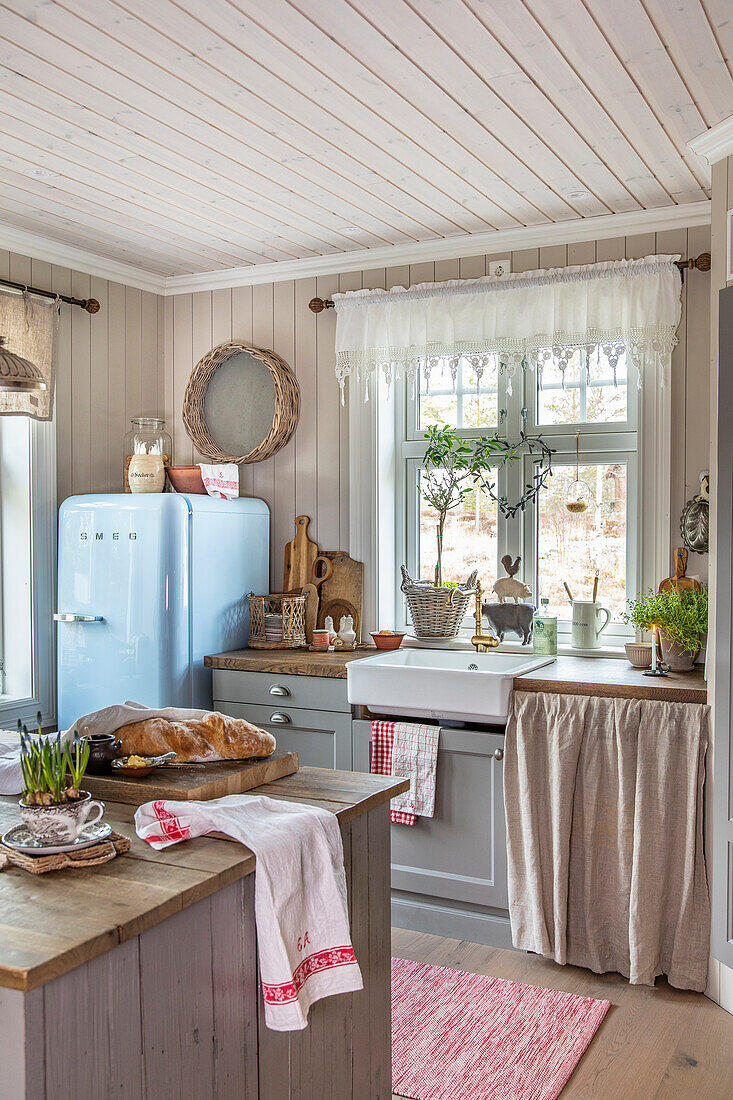 Landhausküche mit hellblauem Retro-Kühlschrank und Holzelementen