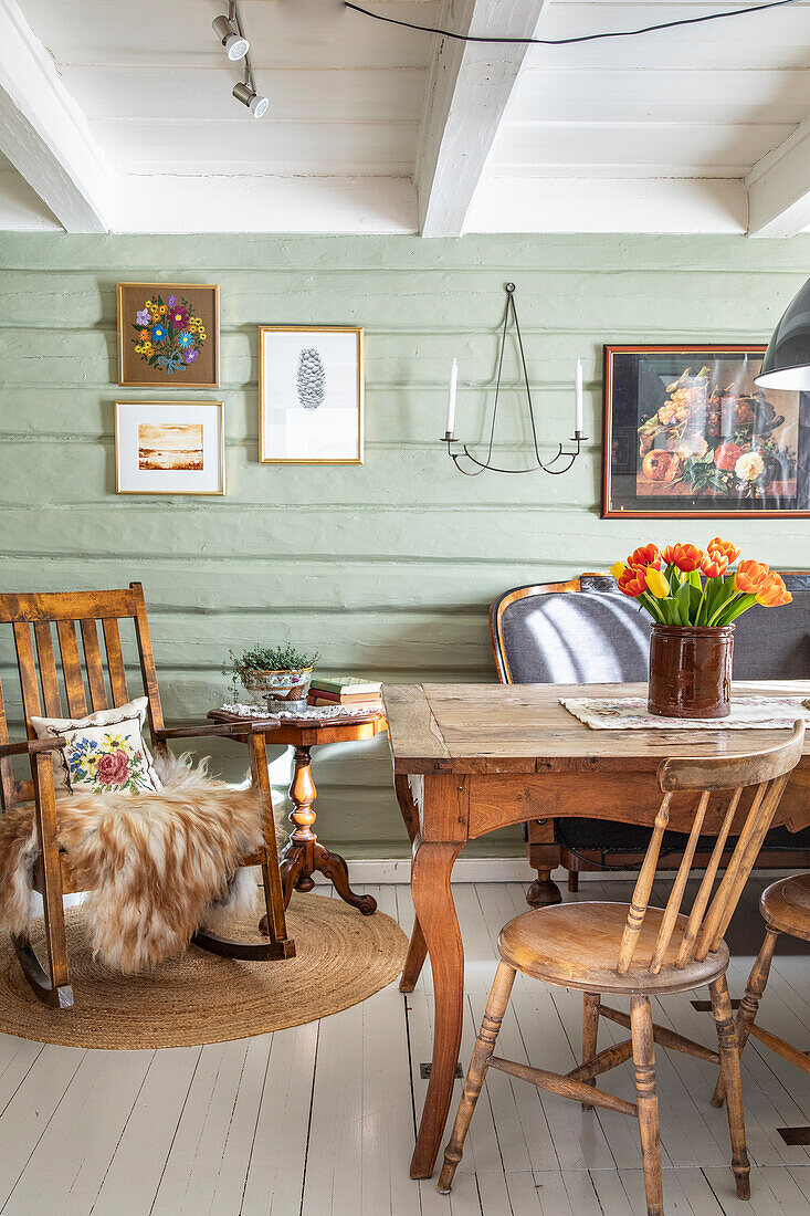 Dining area with rustic wooden table, chairs and pastel green painted wooden wall