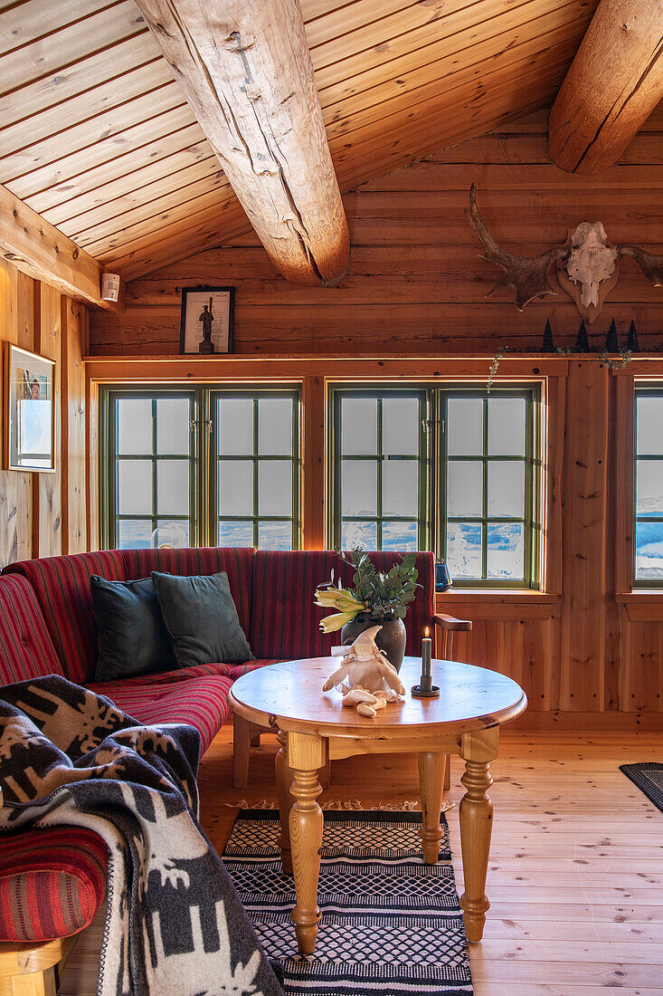 Rotes Sofa und rustikaler Couchtisch in einer Berghütte