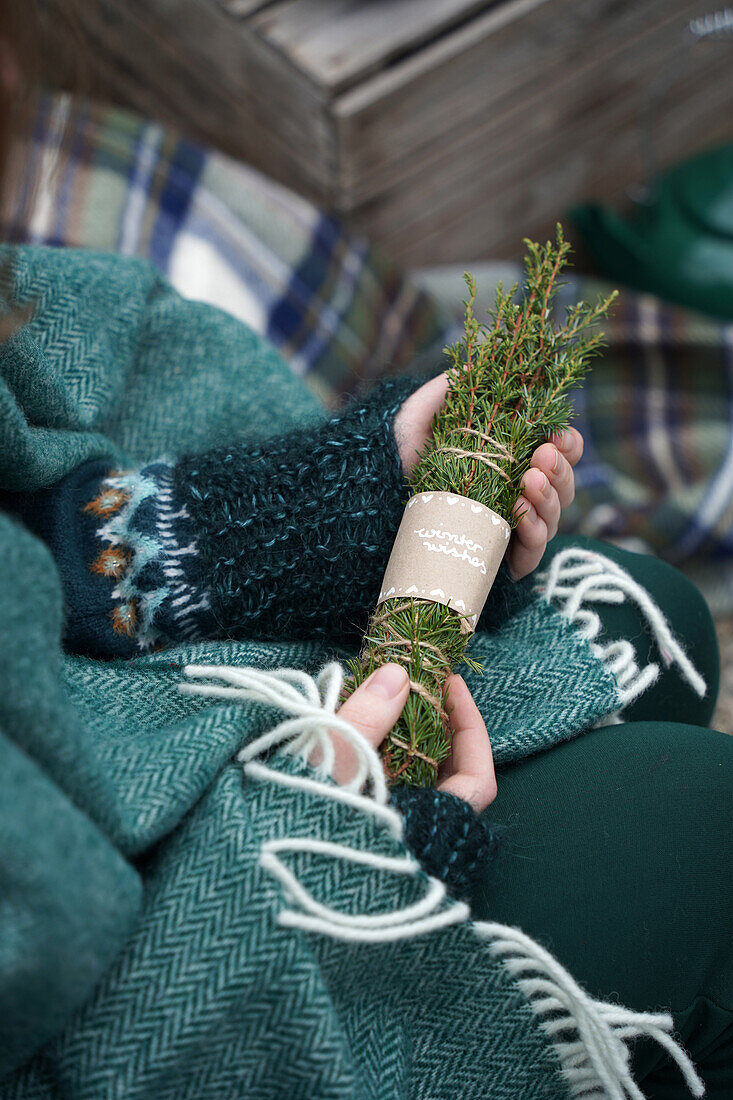 Woman holding bundles of incense made from juniper and spruce branches in her hands