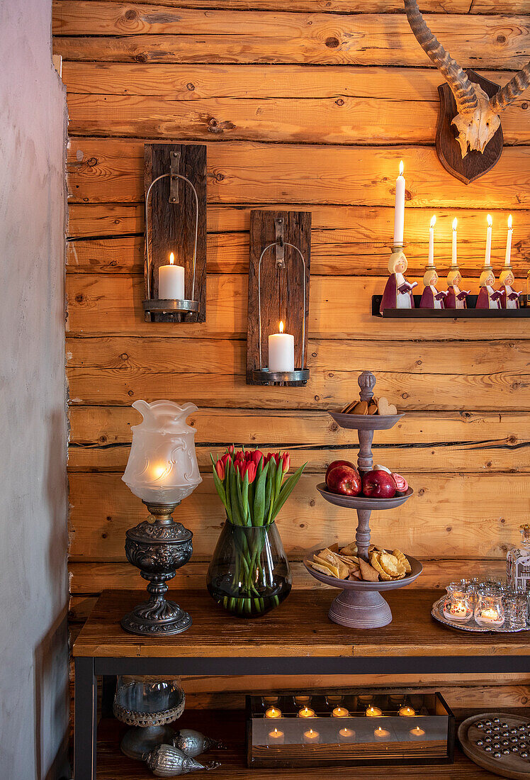 Rustikales Interieur mit Tulpenstrauß und Kerzen auf Holzkonsole