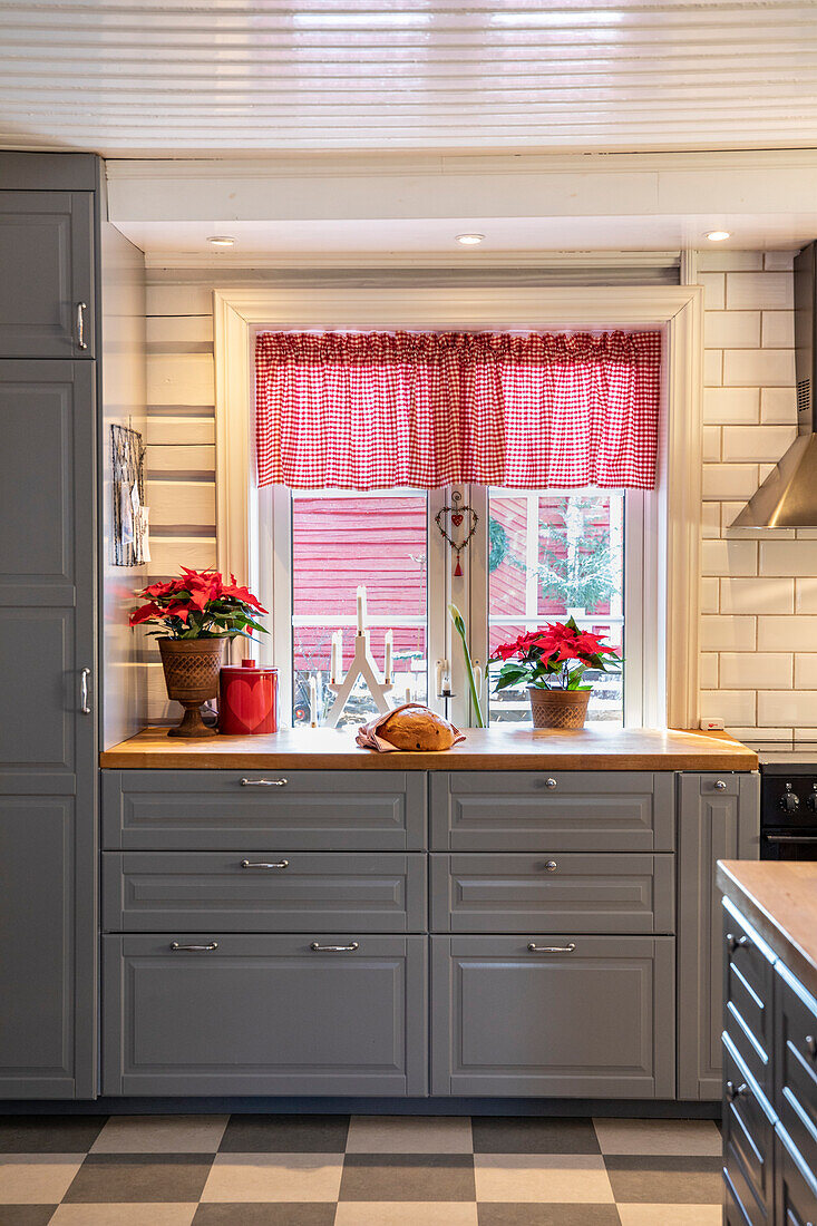 Country kitchen with poinsettias and red and white chequered curtains