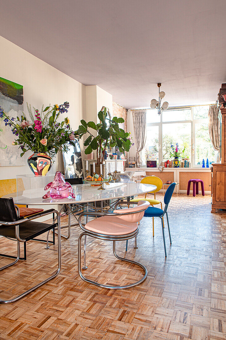 Dining room with parquet floor, marble table and colored chairs