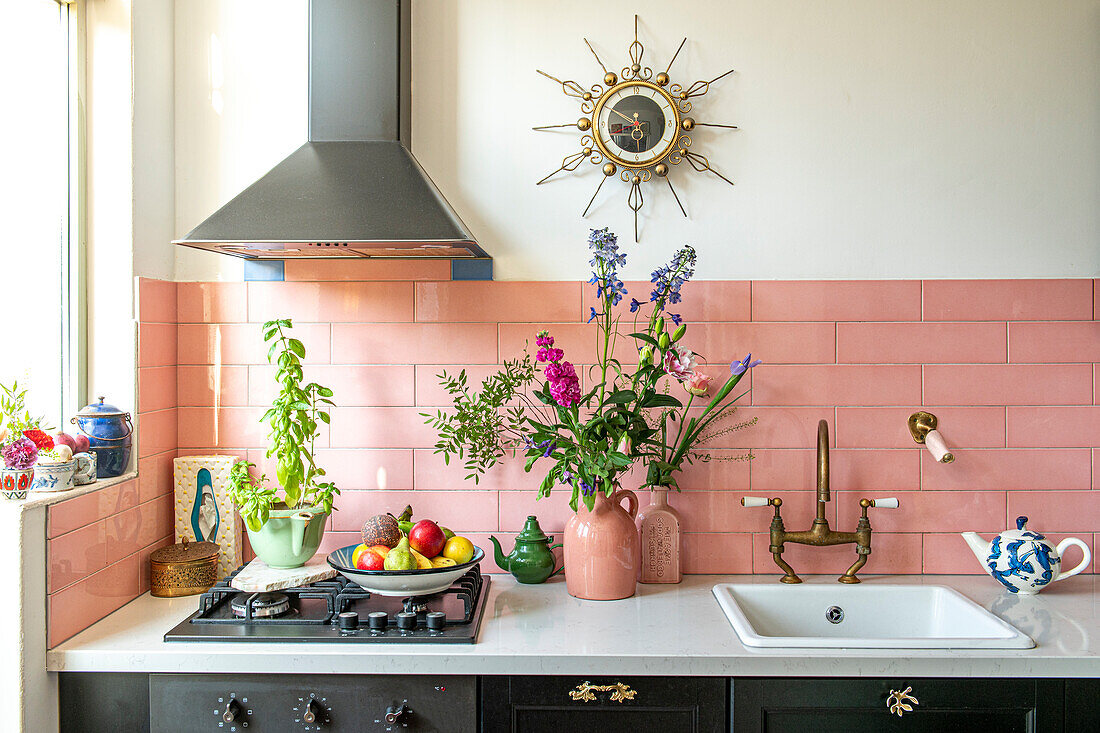 Kitchen with pink tiled backsplash, wall clock and flowers