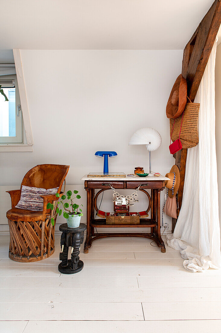 Vintage table, side table with plant and armchair in bright attic room